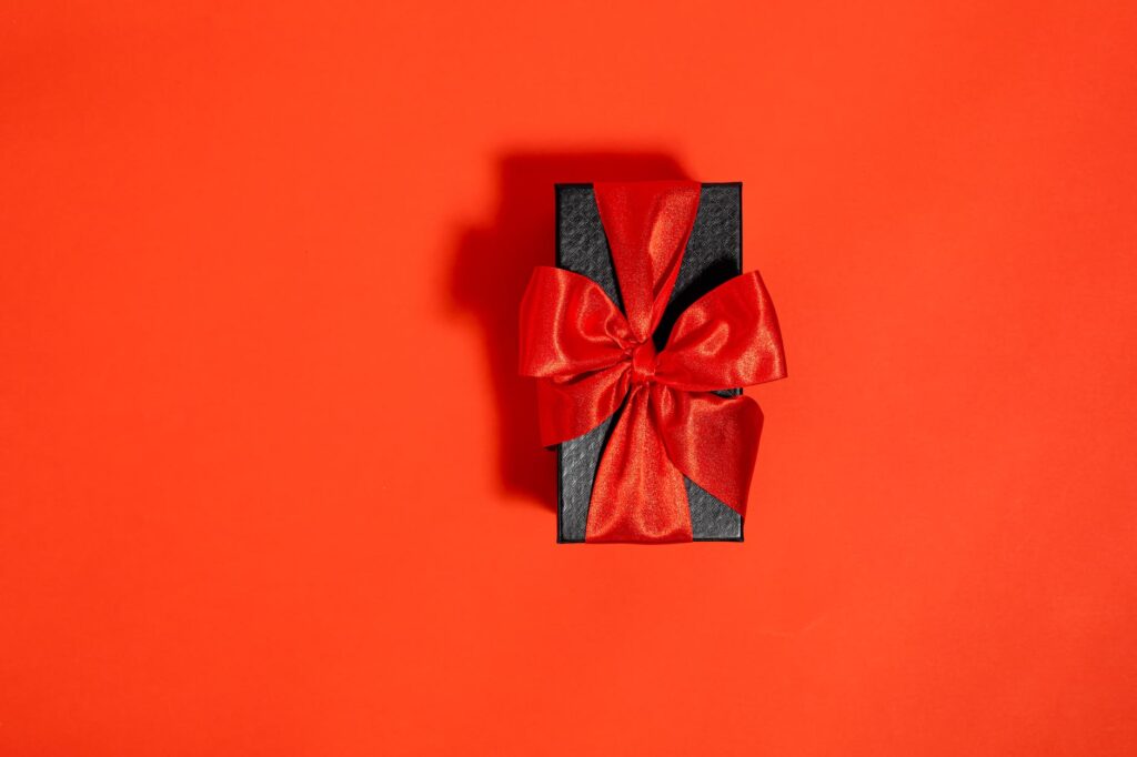 a black box tied with red ribbon on red background